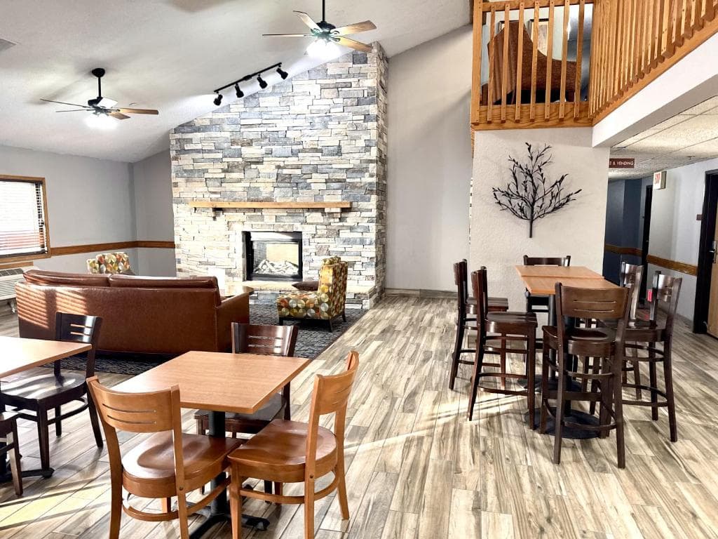 Spacious common area featuring a stone fireplace, leather seating, and wooden dining tables.