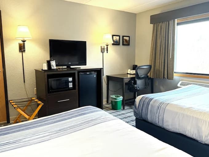 Standard hotel room featuring two beds, a television, microwave, mini-fridge, and a small work desk.